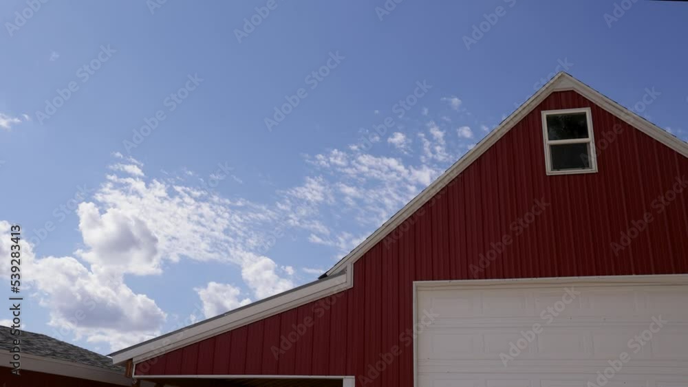 Time-Lapse - Clouds move rapidly over roof of red county barn Time-Lapse - Clouds move rapidly over roof of red county barn