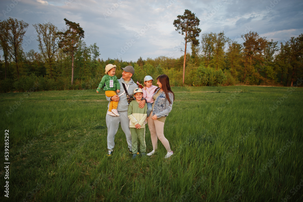 Fototapeta premium Parents with three kids having fun together at meadow.