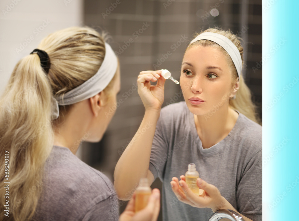 woman looking in the mirror in the bathroom and taking care of her skin. woman looking in the mirror in the bathroom and taking care of her skin.