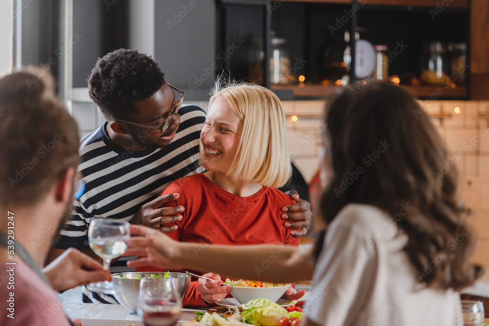 Young diverse people having a holiday party at home, preparing food, drinking, talking, and enjoying Young diverse people having a holiday party at home, preparing food, drinking, talking, and enjoying
