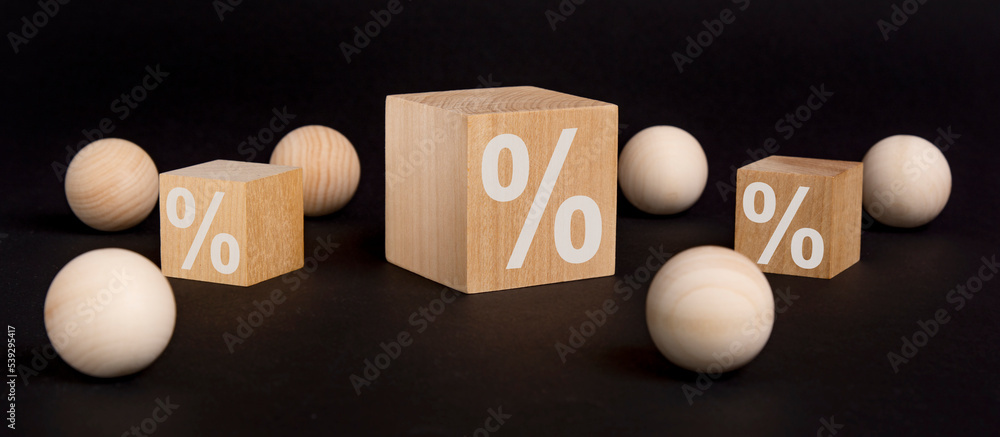 percent sign on wooden cube on black background with wooden balls. concept of sale and discount. percent sign on wooden cube on black background with wooden balls. concept of sale and discount.