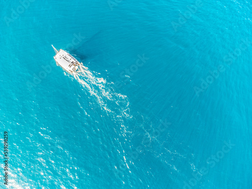 Aerial view of a boat sailing in the turquoise sea in Sardinia