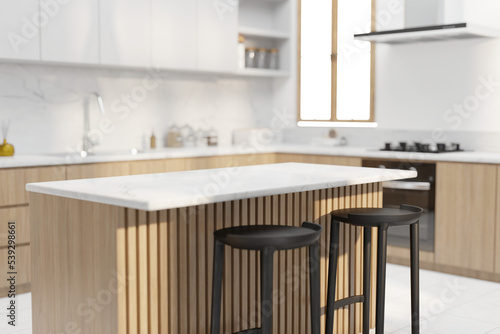 Blurred interior of modern kitchen with white walls, white tile floor, white countertops and wooden cupboards and accents. Table for your product in foreground or as a background image. 3d rendering