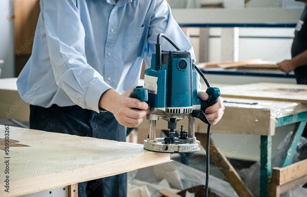 Carpenter working with milling machine. Joinery, woodworking and furniture making, professional carpenter cutting wood in carpentry workshop, industrial concept.