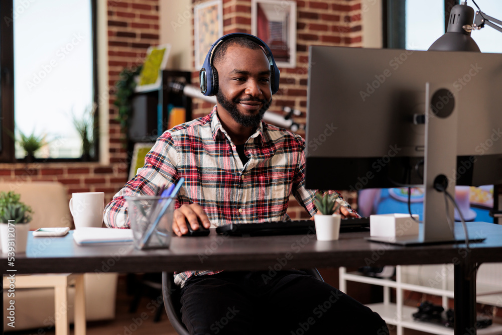 Office employee working from home on computer and listen to music or podcast show online on headphones. Man using headset and browsing internet website, doing remote freelance job. Office employee working from home on computer and listen to music or podcast show online on headphones. Man using headset and browsing internet website, doing remote freelance job.