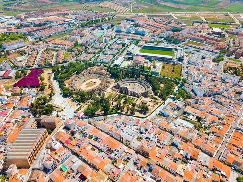 Aerial view of ruins of antique Roman amphitheatre and Theatre on background of modern Merida cityscape, Spain