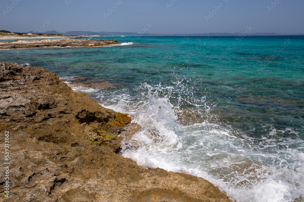 Rocky beach with a turquoise blue sea and waves in spain