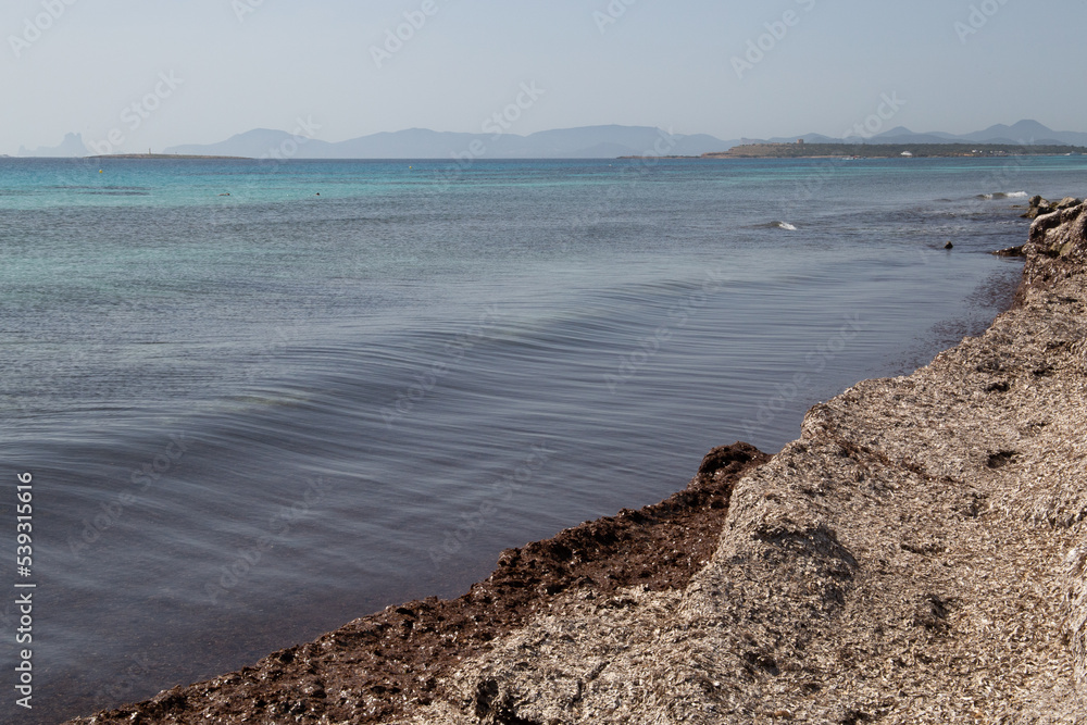 Rocky beach with a turquoise blue sea and waves in spain