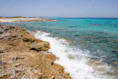 Rocky beach with a turquoise blue sea and waves in spain