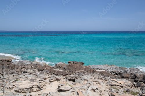 Rocky beach with a turquoise blue sea and waves in spain