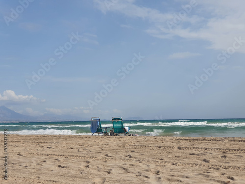 l seaside landscape with two sun loungers on the beach on the shores of the turquoise sea on a warm summer day