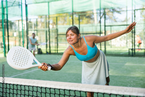 Active womans with enthusiasm playing padel on the tennis court © JackF