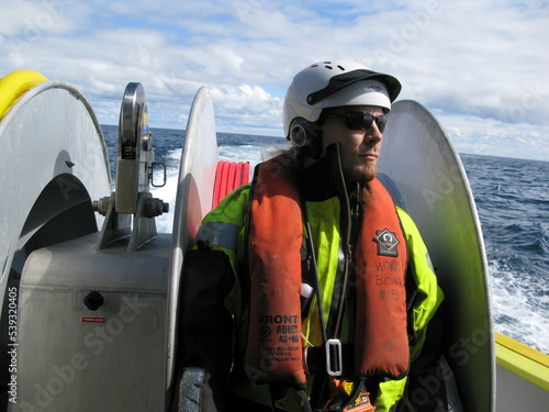Принти на полотні Work boat crew member in high visibility personal protective equipment on small boat back deck
