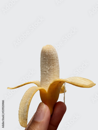 Hand holding peeled yellow fresh banana