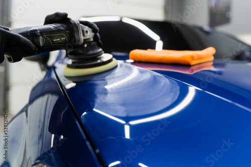 Hard wax car polishing with orbital polisher for remove scratches close-up. Working process in detailing auto service.