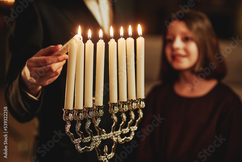 Canvas Print Close up of jewish man lighting silver menorah candle during Hanukkah celebratio