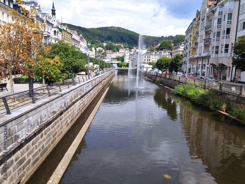 Obraz premium Karlove Vary Chech fountain, river and white road with trees