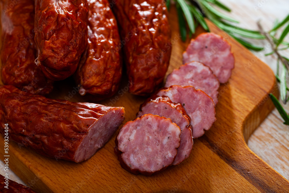 Sliced half-smoked sausages susena on wooden table. Traditional Chezh meat products. High quality photo