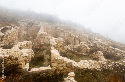 View of remains of ancient stone houses at archaeological site of Sagalassos on misty winter day, Turkey photo