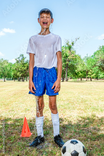 Canvas Print Male youth soccer player standing on the field soaking wet