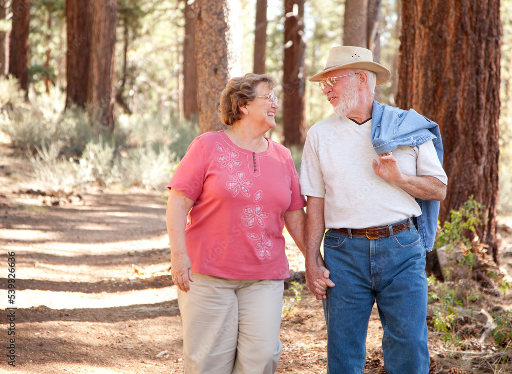 Loving Senior Couple Hold Hands Walking Together In a Forest Loving Senior Couple Hold Hands Walking Together In a Forest