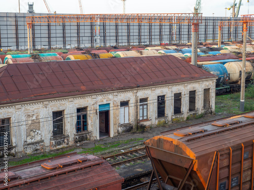 Old abandoned station building. Creepy places. Sunset at the train station. The cargo part of the station is an industrial zone against the backdrop of mountains. Fuel wagons. photo