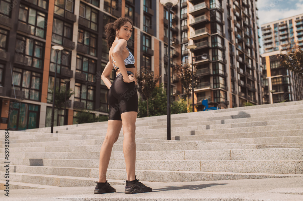 Fit girl in tight sportwear standing on the urban background
