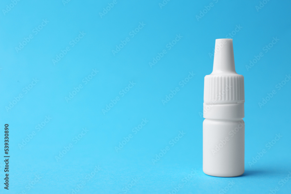Bottle of medical drops on light blue background. Space for text Bottle of medical drops on light blue background. Space for text