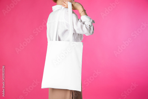 Woman with white textile bag on pink background, closeup. Space for design