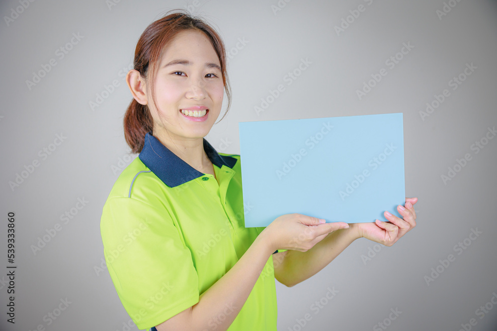 水色のメッセージボードを持つ作業服の日本人女性（左向き）
