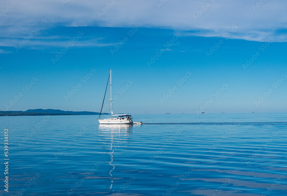 Yacht sailing across completely calm Lake Champlain from Vermont