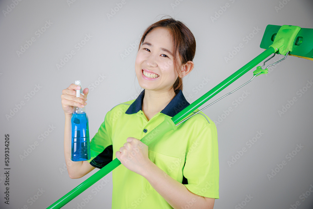 スプレーと掃除モップを持つ蛍光色の清掃服を着た日本人女性