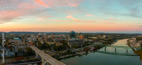 aerial shot of the Henley Street Bridge and Gay Street Bridge over the Tennessee River surrounded by autumn colored trees, lush green trees and office buildings with powerful clouds at sunset photo