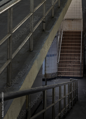 Stairs leading to interior view of public underpass with white tiled walls and CCTV. Space for text, Selective focus.