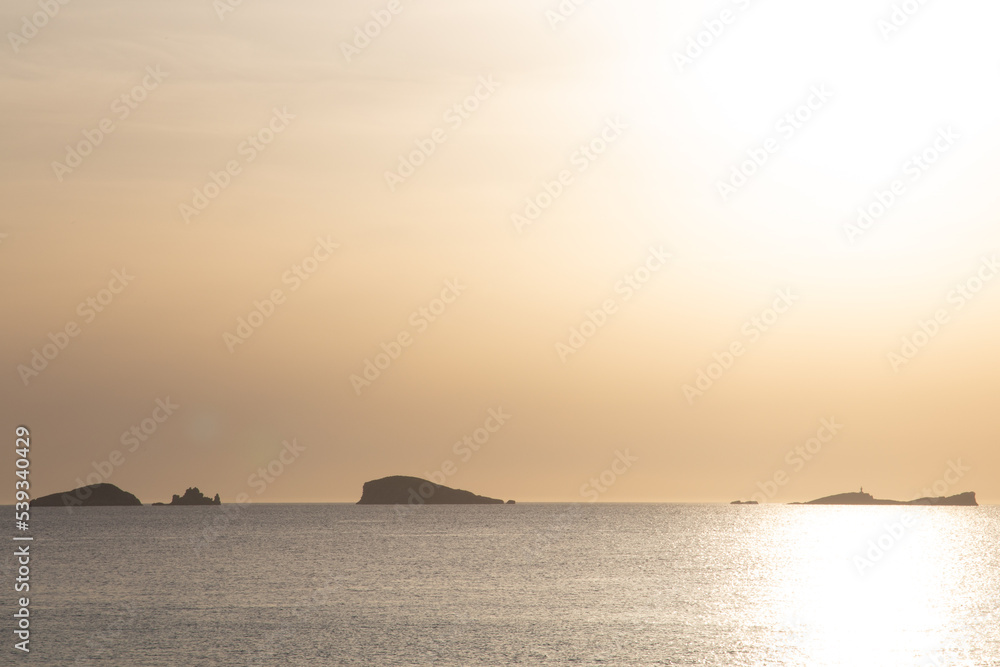 Sunset on the island of Ibiza with the sun setting on the horizon and orange colors in the sky Sunset on the island of Ibiza with the sun setting on the horizon and orange colors in the sky
