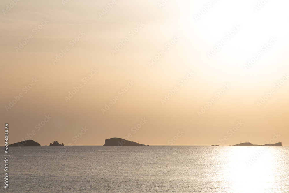 Sunset on the island of Ibiza with the sun setting on the horizon and orange colors in the sky