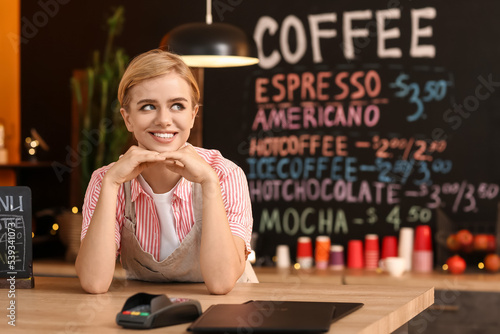 Young female barista at tab...
