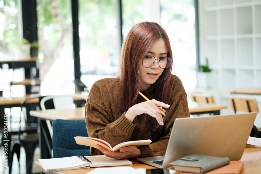Woman learning online using laptop and writing notes. Woman learning online using laptop and writing notes.