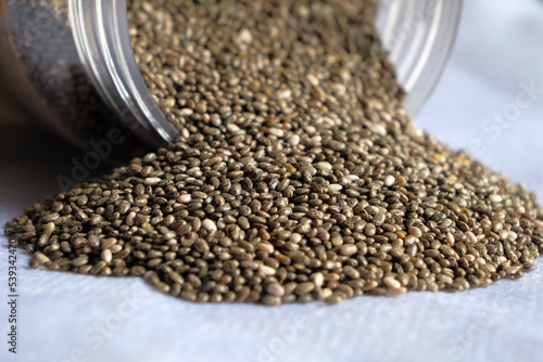Close-up of chia seeds scattered from glass jars on white background. Copy space.