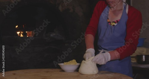 Female Baker Putting Cheese Inside Dough, Preparation Of Meskhetian Bread - medium shot photo