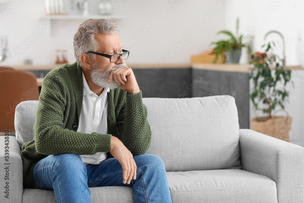 Thoughtful mature man sitting on sofa in kitchen Thoughtful mature man sitting on sofa in kitchen