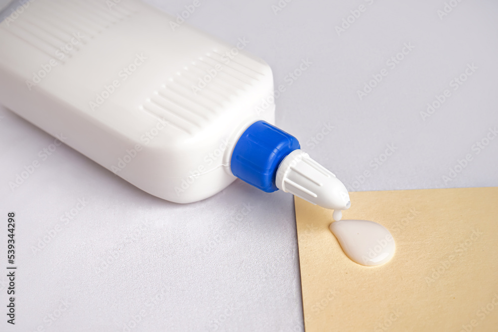 Bottle of glue and paper sheet on light background, closeup Bottle of glue and paper sheet on light background, closeup
