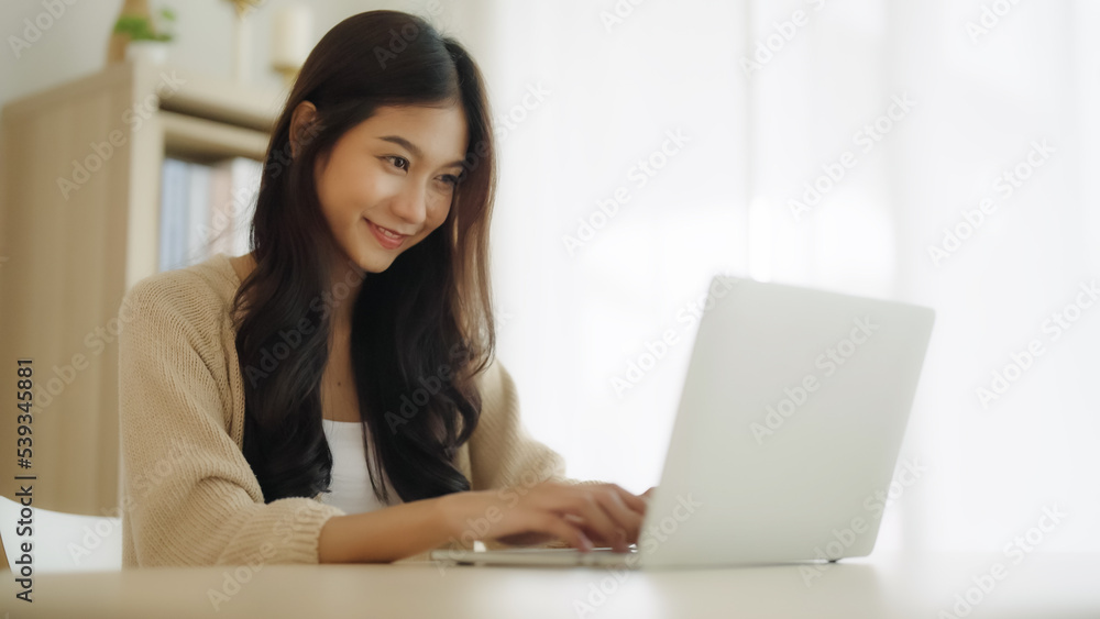 Young asian woman working at home. Female using computer laptop on desk at house Young asian woman working at home. Female using computer laptop on desk at house