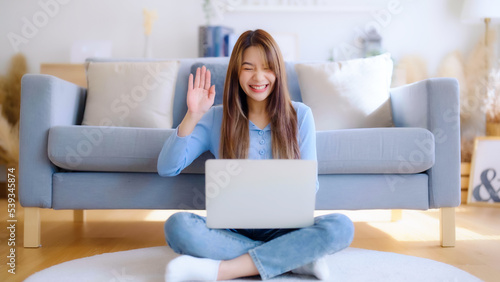Young asian woman working on her laptop at home, grinning. attractive Asian woman utilizing computer for online schooling, video calling, and conference calls