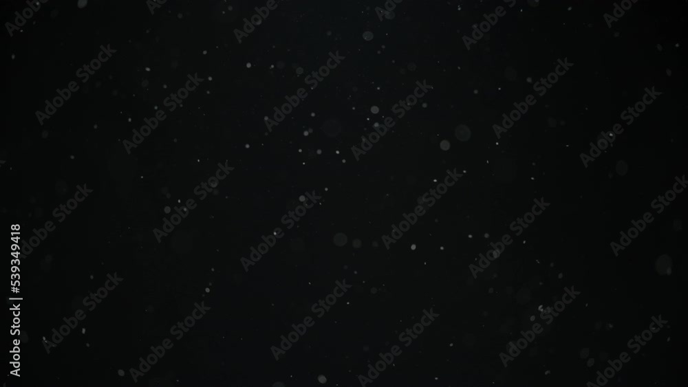 Real dust particles floating in the air on black background. Slow motion.