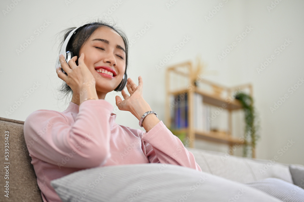 Peaceful and relaxed Asian woman wearing headphones, eyes closed, enjoying with the music Peaceful and relaxed Asian woman wearing headphones, eyes closed, enjoying with the music