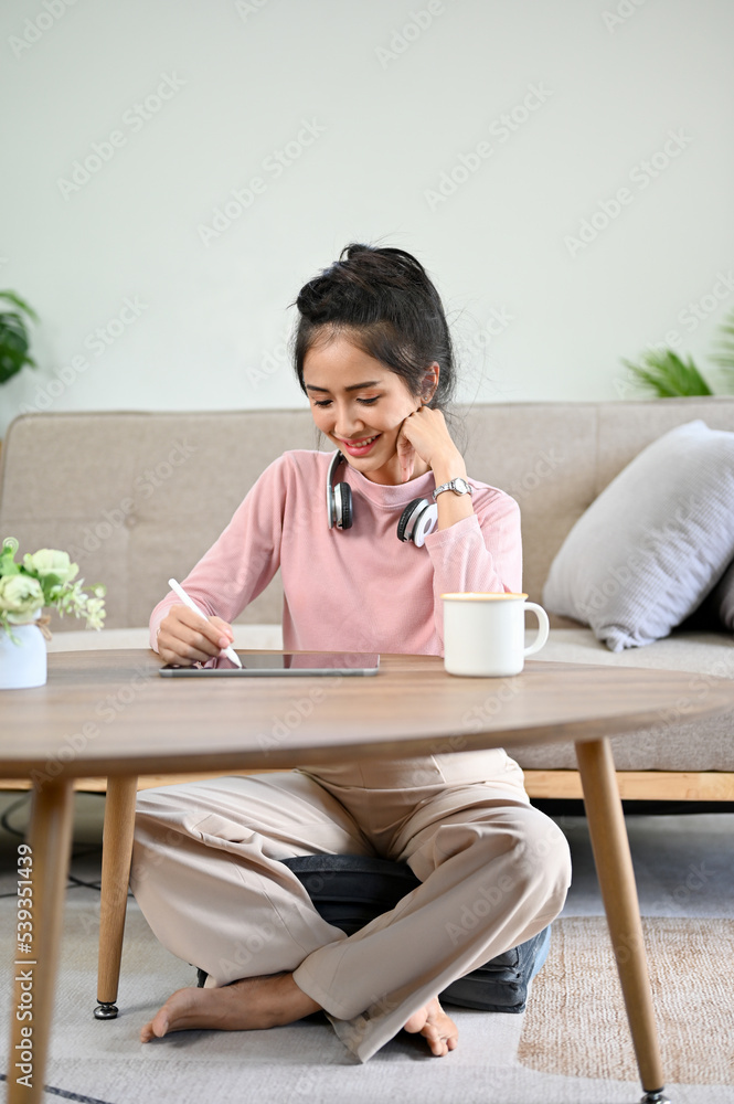 Pretty Asian female college student doing homework in her living room. Pretty Asian female college student doing homework in her living room.