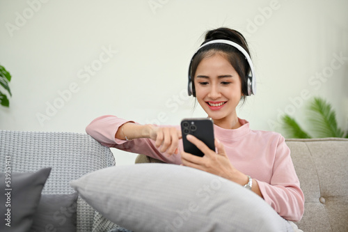 Charming Asian female refreshing her day with podcast or listening to music through headphones
