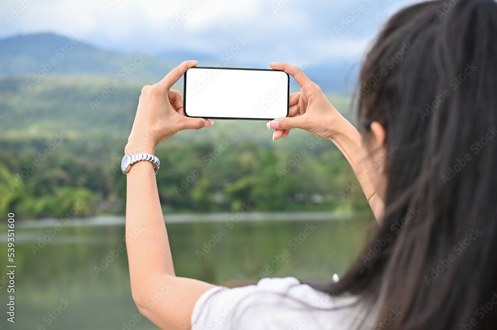 close-up image, Asian female using her smartphone to taking a picture of beautiful green mountain