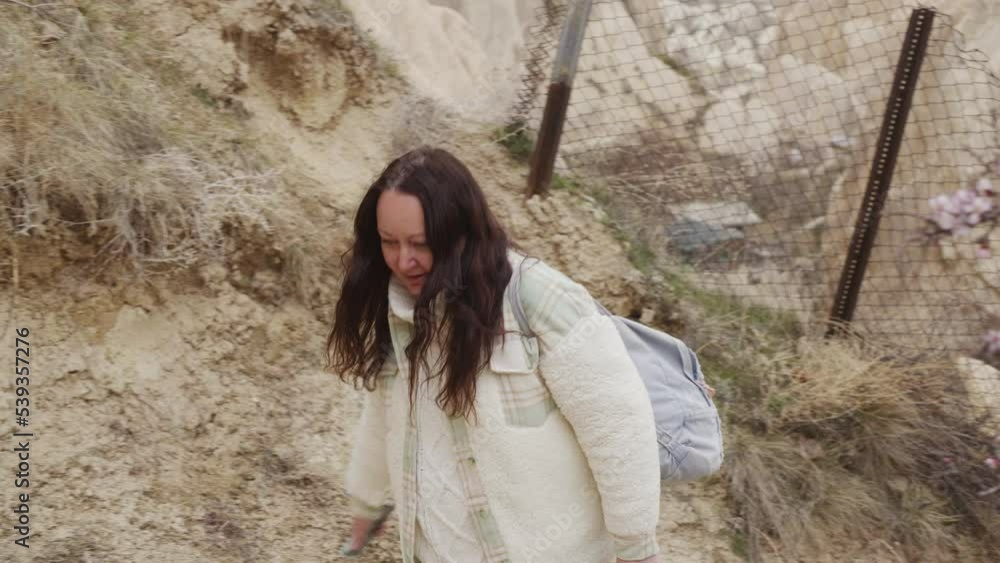 Happy woman walking up to hill mountain in sandy canyon, park. Hiking with backpack climbing up. Weekend trip, trekking alone, travelling and discovering new destinations. Happy woman walking up to hill mountain in sandy canyon, park. Hiking with backpack climbing up. Weekend trip, trekking alone, travelling and discovering new destinations.
